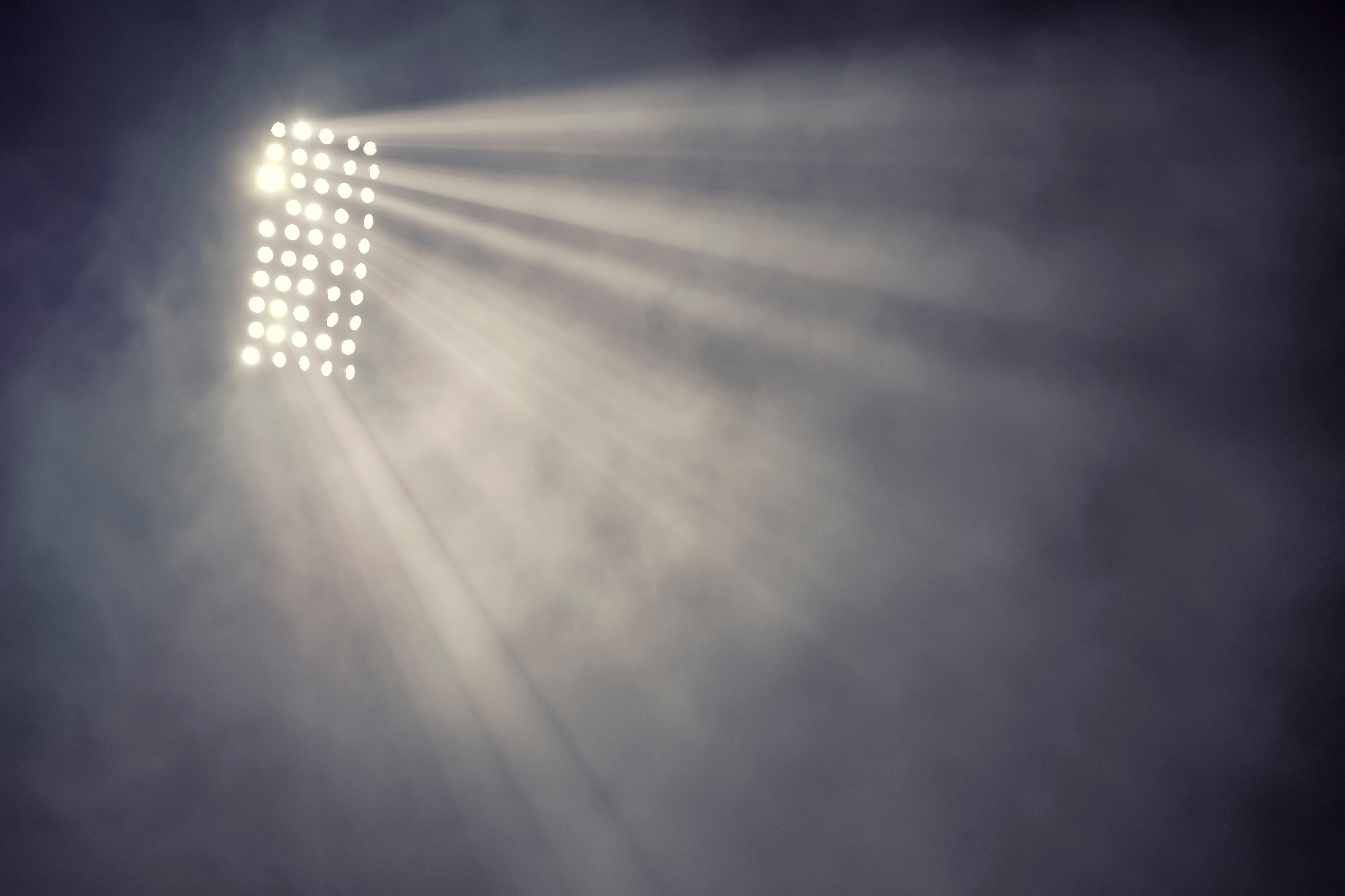 Stadium floodlights and smoke against a dark night sky
